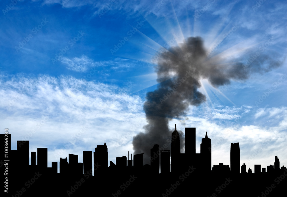 Fototapeta premium Silhouette of the city with smoke against cloudy sky