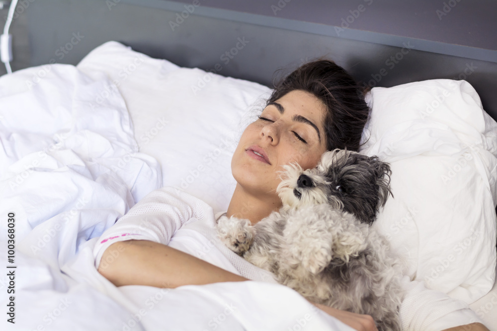 young woman sleeping with her small dog in a human bed. young woman sleeping with her small dog in a human bed.