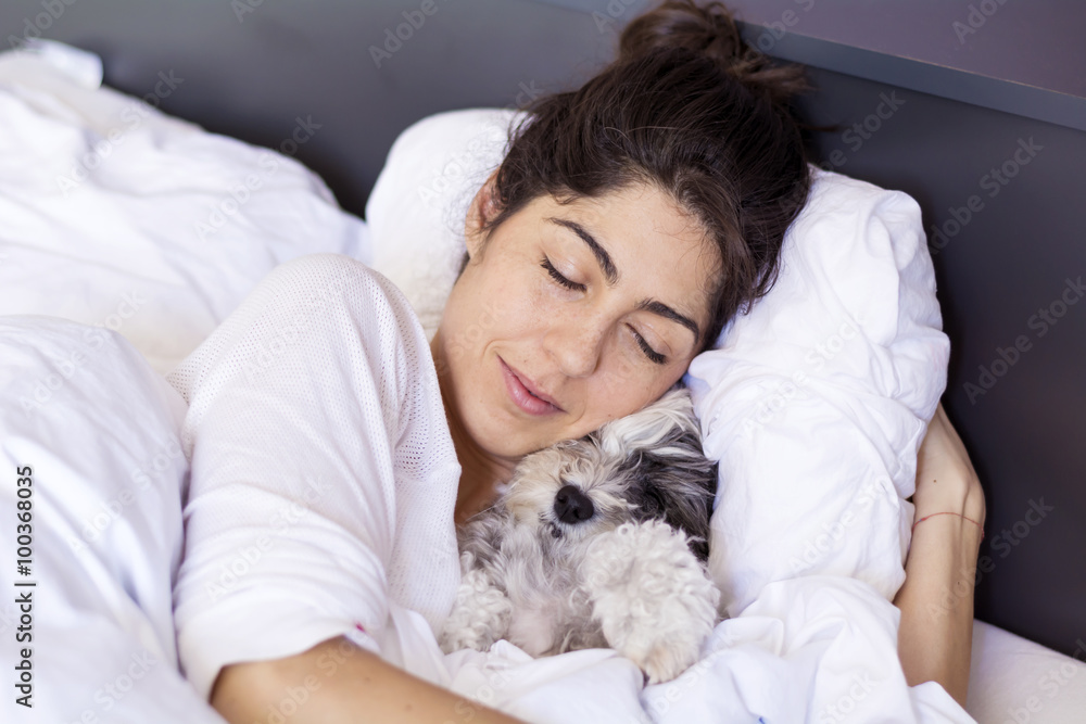 young woman sleeping with her small dog in a human bed. young woman sleeping with her small dog in a human bed.