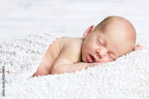adorable newborn boy sleeps on the white blanket with background