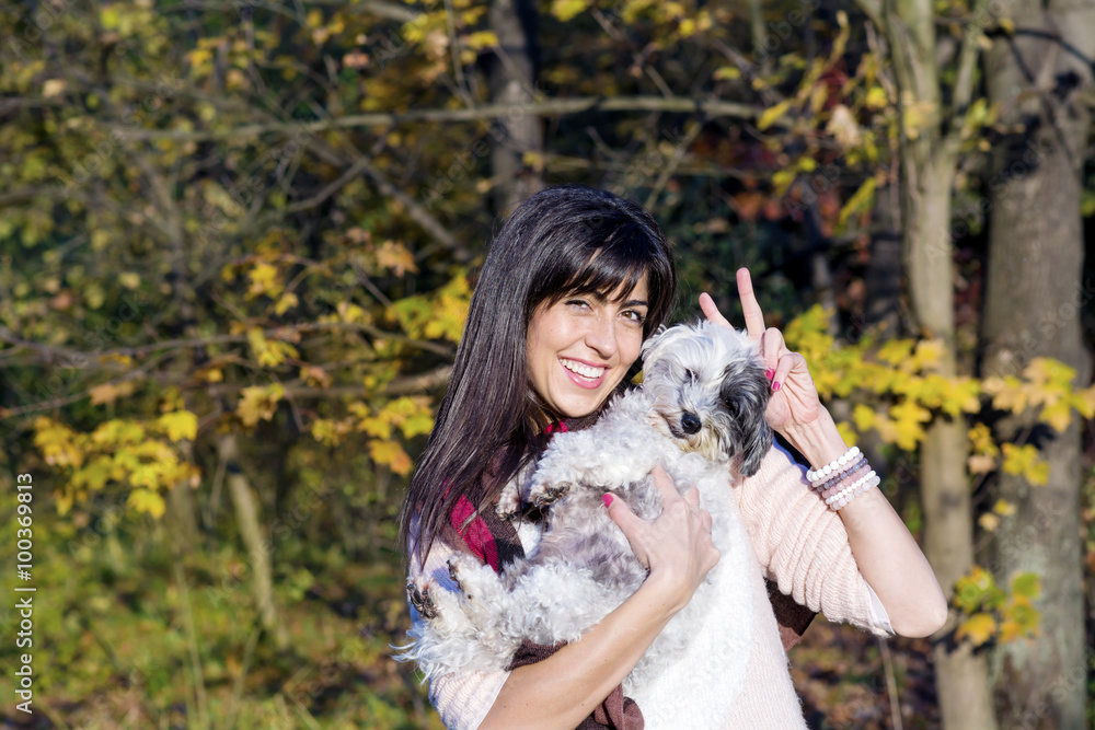 beautiful smiling young woman hugging her small white poodle dog in the autumn park beautiful smiling young woman hugging her small white poodle dog in the autumn park