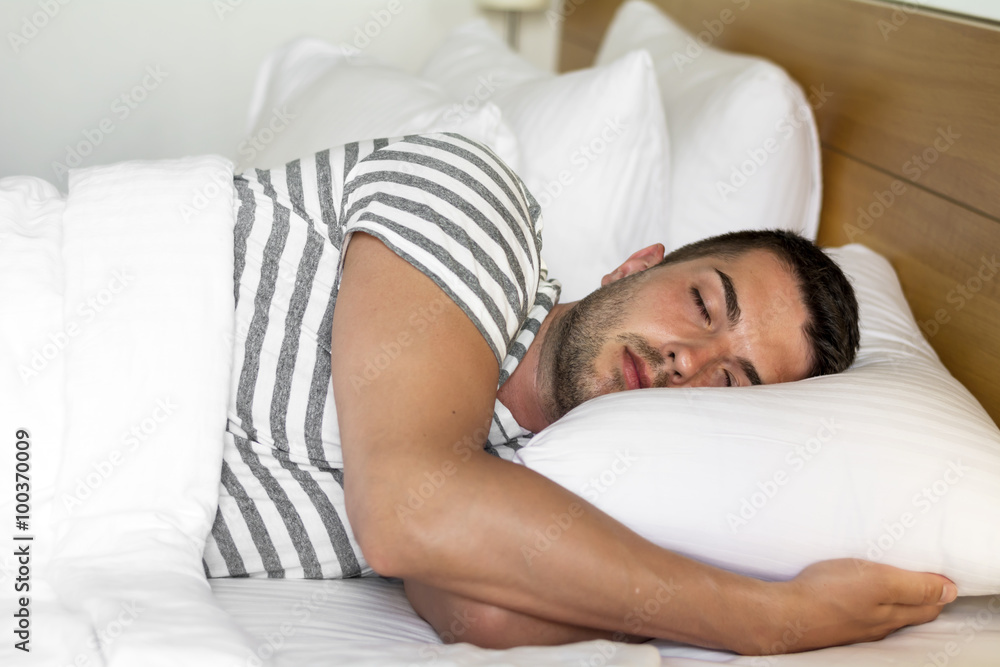 Handsome young man happily sleeping in white bed Handsome young man happily sleeping in white bed