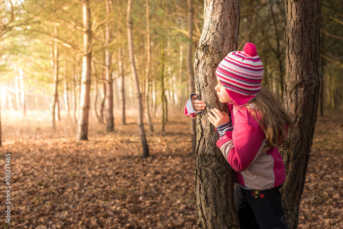 Canvas Print Girl hiding behind a tree