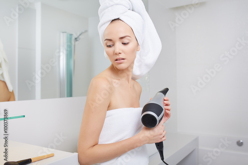 The girl in the bathroom with hairdryer in hand