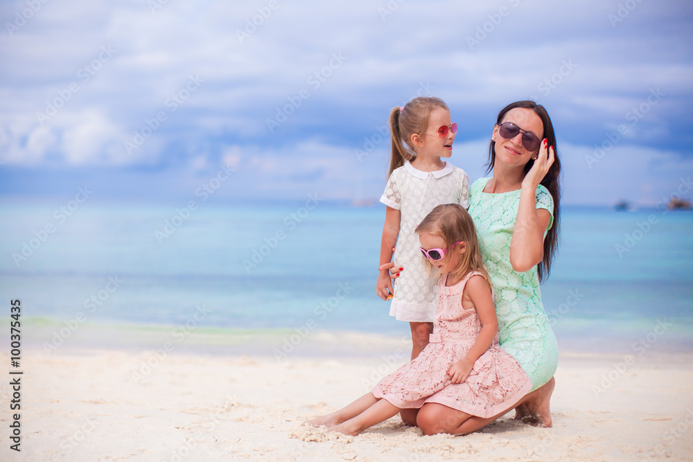 Adorable little girls and young mother on tropical white beach 