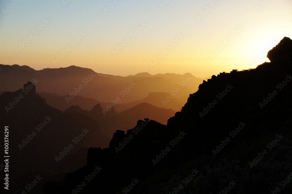 Mountain ridges colored by the setting sun. Silhouettes fading near horizon.
