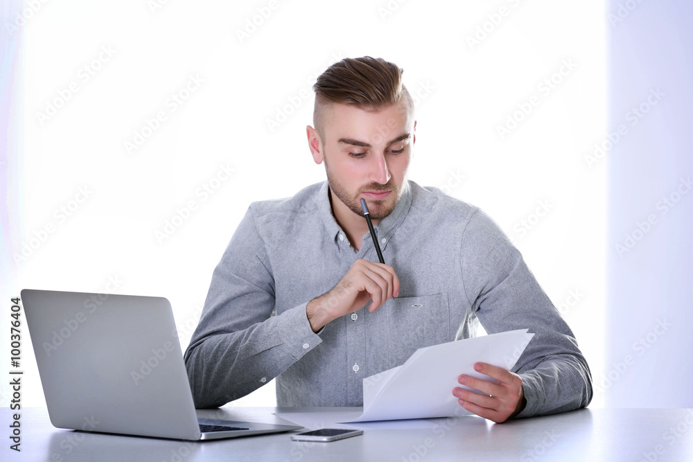 Businessman working with laptop on bright background Businessman working with laptop on bright background