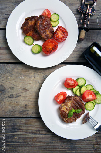 Roasted beef fillet and fresh vegetables on plate, on wooden background