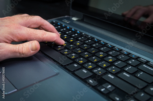 Man typing on a keyboard with letters in Hebrew and English - Laptop keyboard_Dark atmosphere