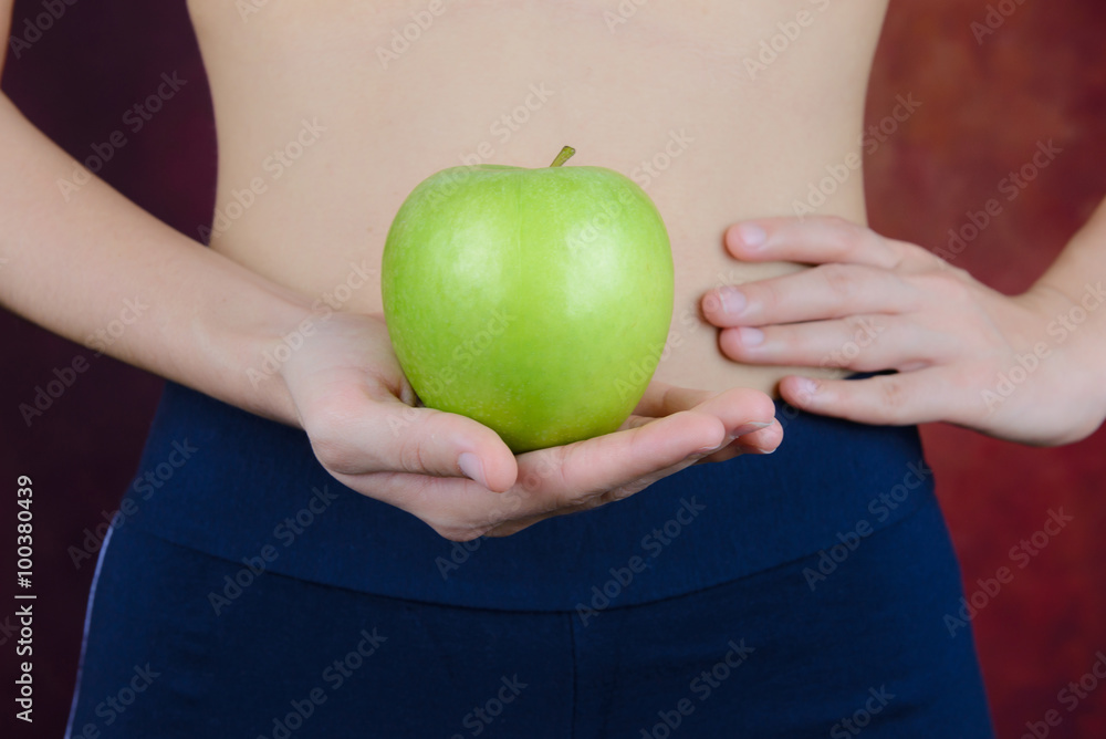 slim woman carries green apple in hand