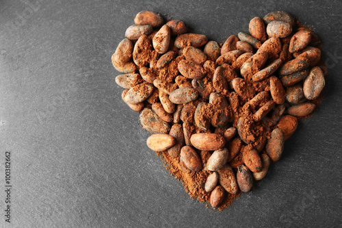 Heart made of aromatic cocoa beans on grey background