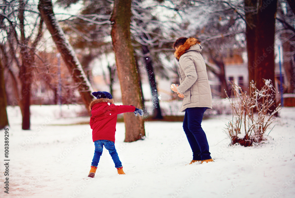 active father and son playing snowballs in winter park active father and son playing snowballs in winter park