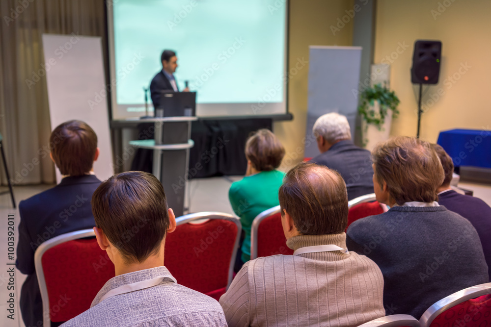 Obraz premium business meeting in a conference hall: people sitting rear and speaker near the empty screen