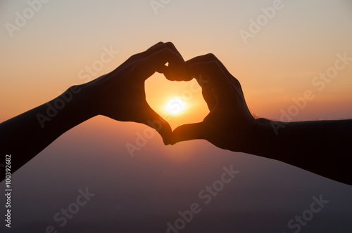Lovers couple hands in Valentine' s heart with sunset background