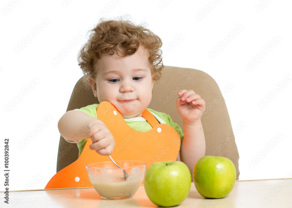 little child eats with spoon sitting at table with fruits little child eats with spoon sitting at table with fruits