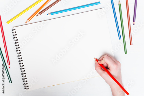 Girl draws with colored pencils on paper