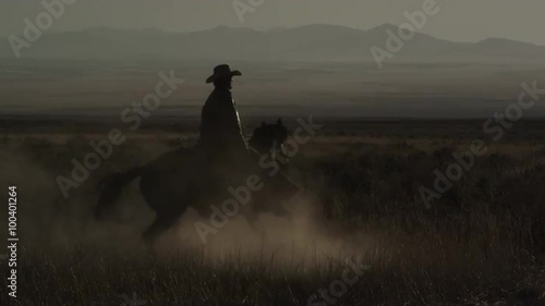 Cowboy riding a horse while turning around at dusk