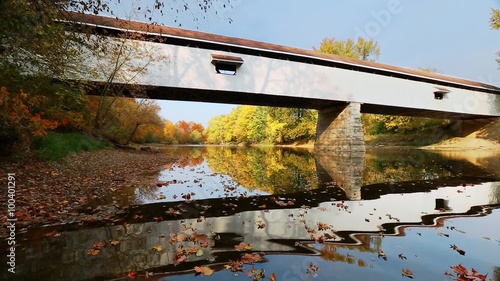 Loop features Potter's Covered Bridge, built in 1870, reflected in the waters of Indiana's White River flowing with colorful autumn leaves floating on the surface. photo