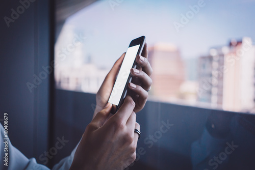 Girl holding her smarthone on the blurred city background. Horizontal photo