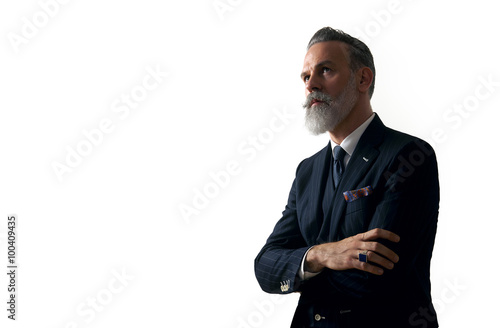 Portrait of bearded gentleman wearing trendy suit and stands against the empty white wall. Horizontal photo