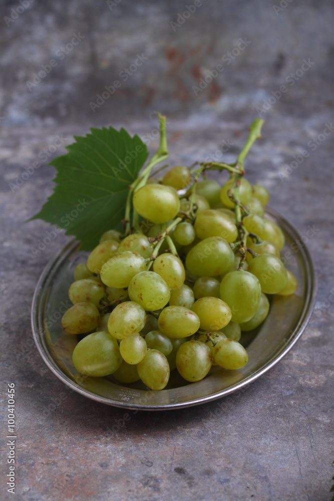 green grapes in a metal plate on a gray background