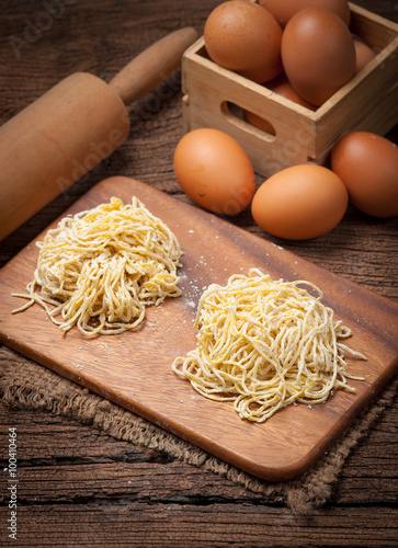 Yellow noodles drying with eggs on wood background