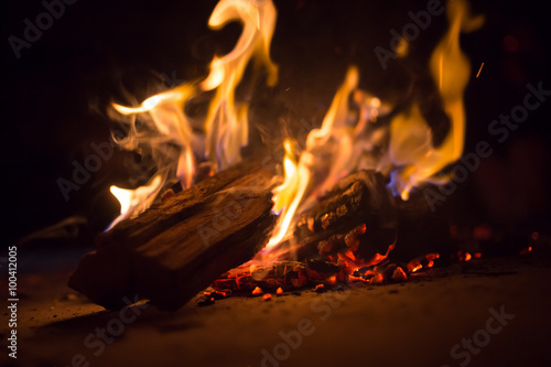 A flaming log smoldering on embers in the dark