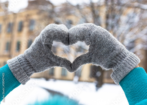 Woman make heart with hands in winter park. Romntic concept photo