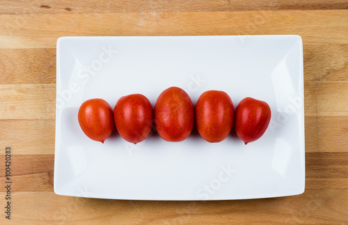 pomodori su piatto bianco sopra a un tagliere, posizione orizzontale photo
