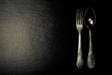 Metal fork and spoon on a black background. Toned