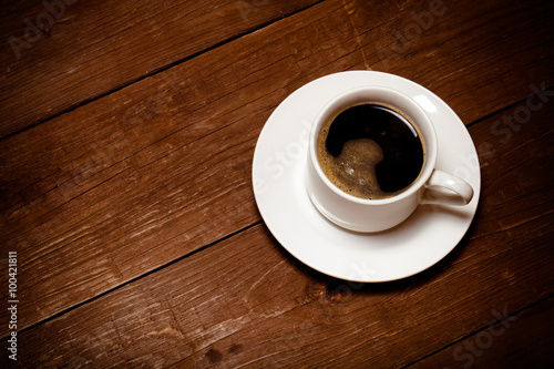 White cup of coffee on old wooden table. Toned