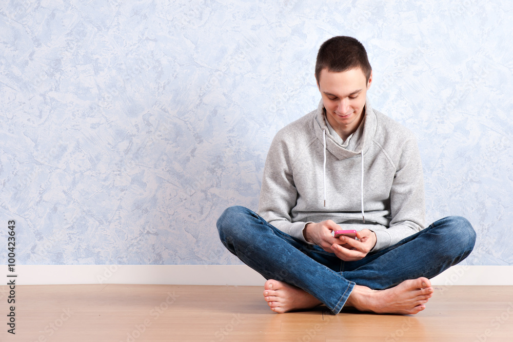 portrait of young man sitting on the floor using a cellphone, isolated. ready for your design
