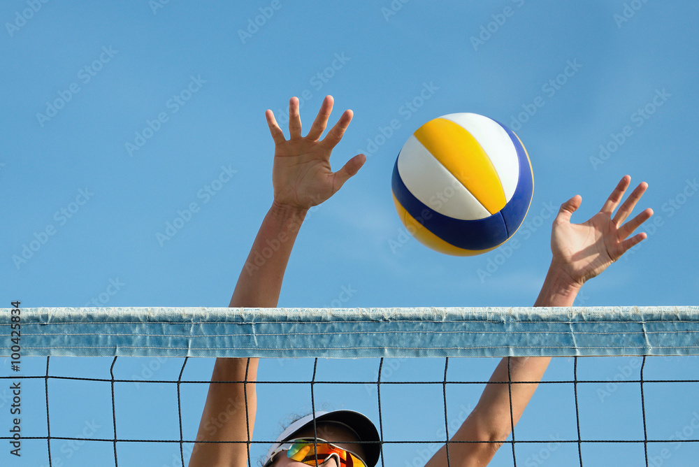 Beach volley ball player jumps on the net and tries to blocks the ball