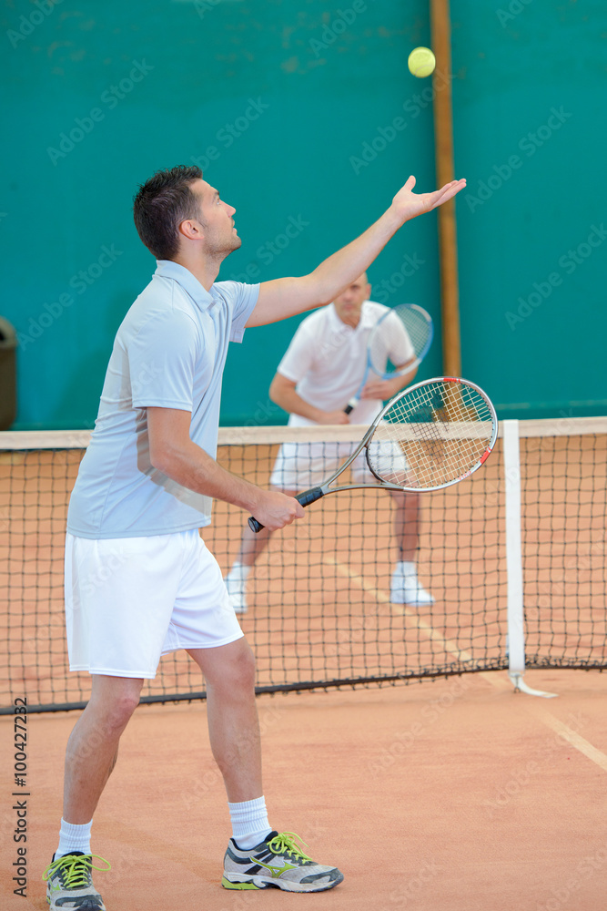 young man doing tennis service