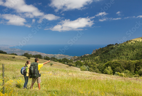 Couple with backpacks on green field