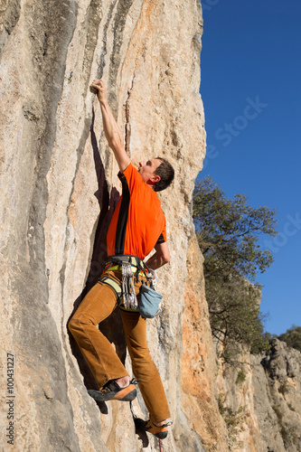 Young male climber hanging by a cliff. © vetal1983