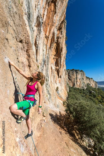 Hippie Style Female Climber ascending Vertical Orange Rock