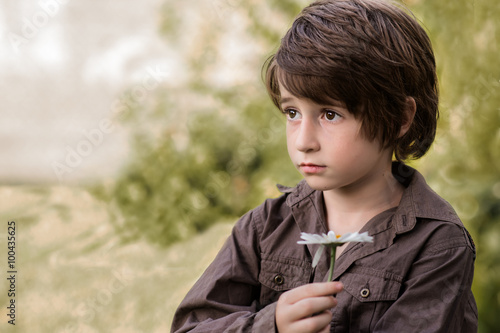 Boy holding a marguerite daisy flower photo