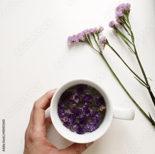 Hand holding a cup of floral forget-me-not flower tea photo