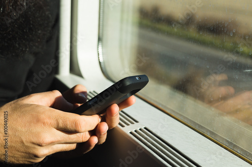man chatting with his smart phone seated on train travelling