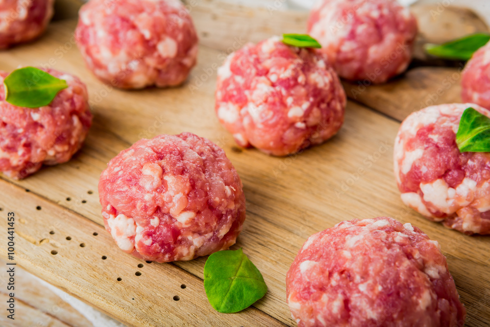 Raw meatballs of beef and pork on a wooden board Raw meatballs of beef and pork on a wooden board