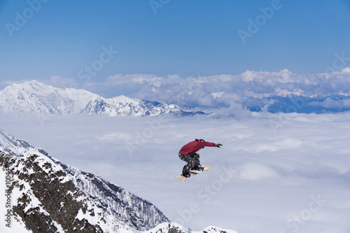 Flying snowboarder on mountains. Extreme sport.