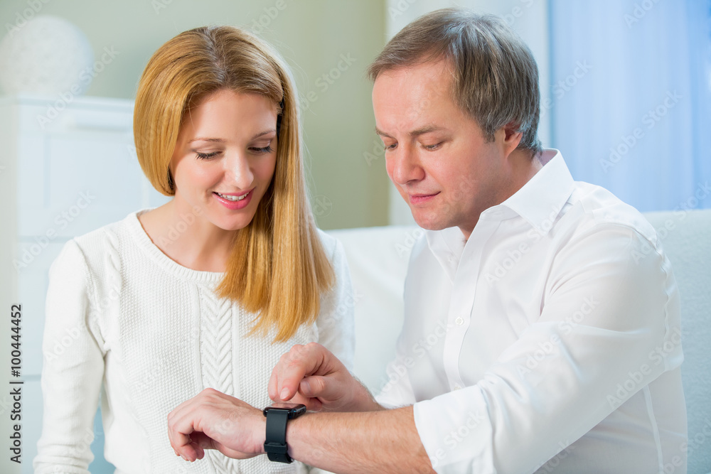 Woman and Man in white shirt sitting on the sofa and looking at smart watch. Showing how to use
Woman and Man in white shirt sitting on the sofa and looking at smart watch. Showing how to use