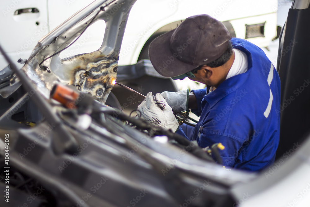 Man mechanical worker repairing a car body in a garage Man mechanical worker repairing a car body in a garage