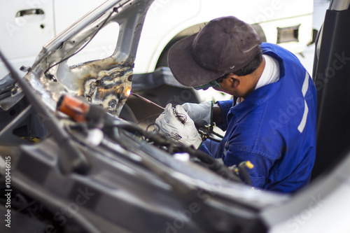 Man mechanical worker repairing a car body in a garage