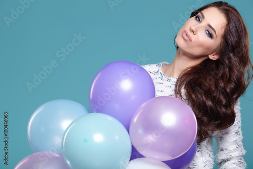 Happy young woman standing over blue wall and holding pink and w © ZoomTeam