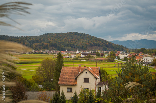 View from the hill of a house, fields and village with the background of rain clouds.