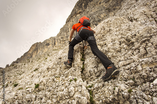 Man climbing in Dolomites with via ferrata equipment / Dolomiti