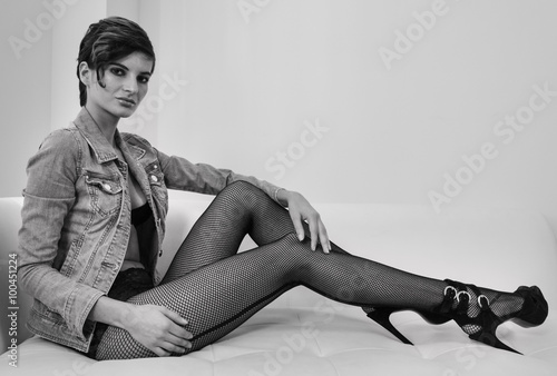 Εκτύπωση καμβά Picture of female model sitting on the sofa and showing legs in fishnet hosiery