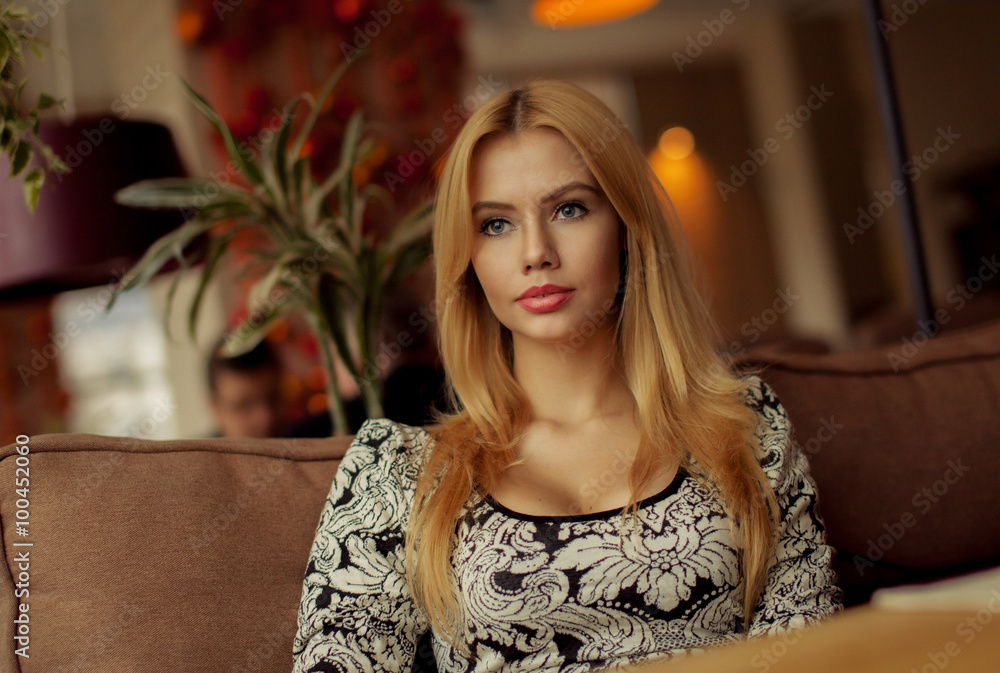 Portrait of a cute blonde smiling woman sitting in a cafe with a cap of coffee Portrait of a cute blonde smiling woman sitting in a cafe with a cap of coffee